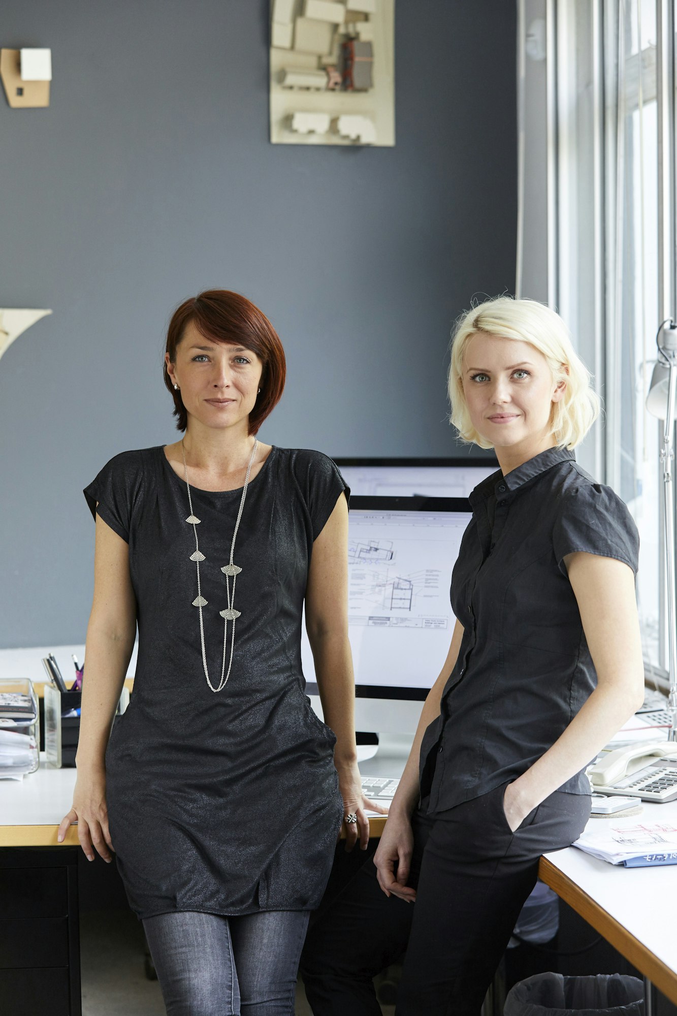 Portrait of two confident female designers at office desk
