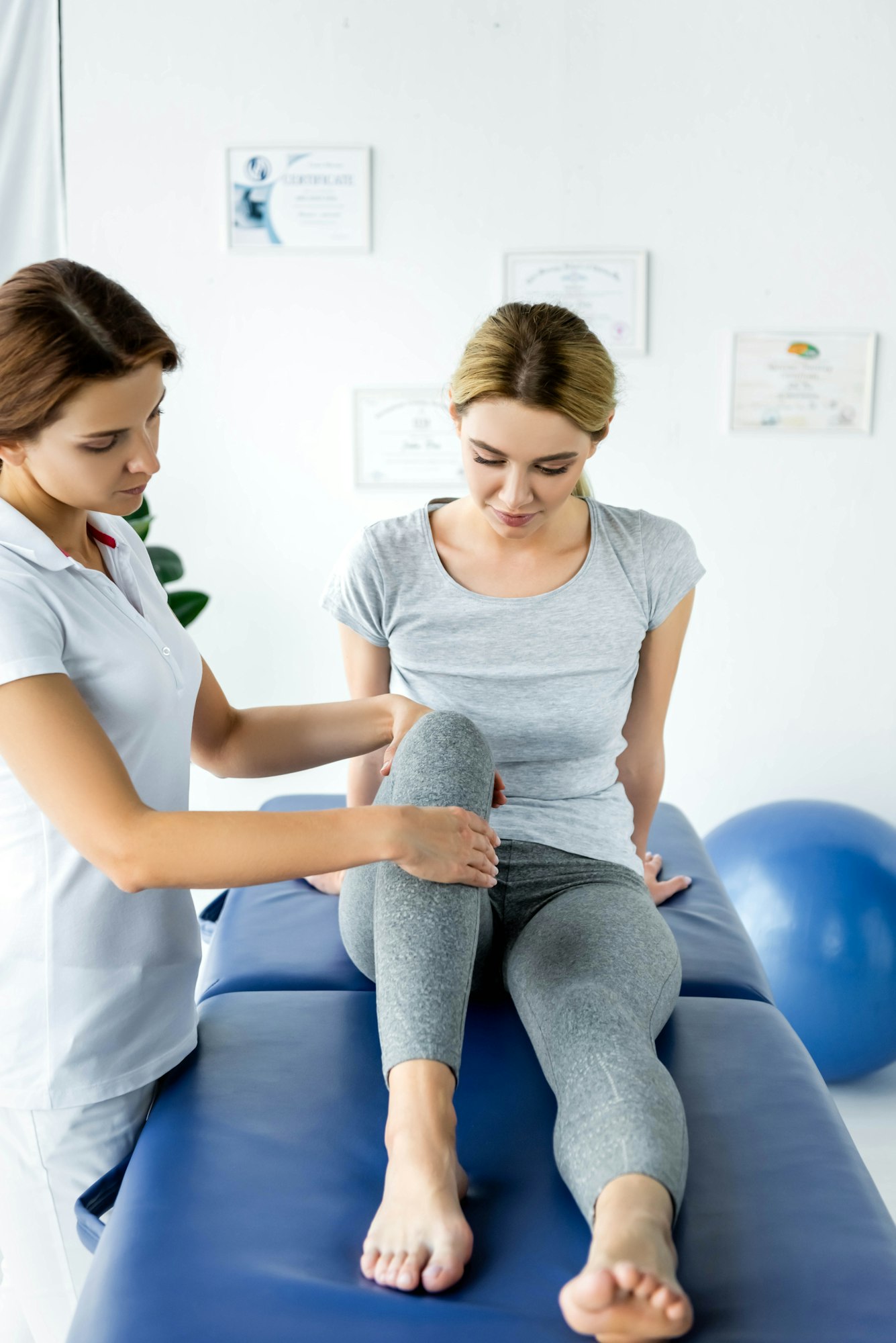 chiropractor touching leg of attractive patient in grey t-shirt