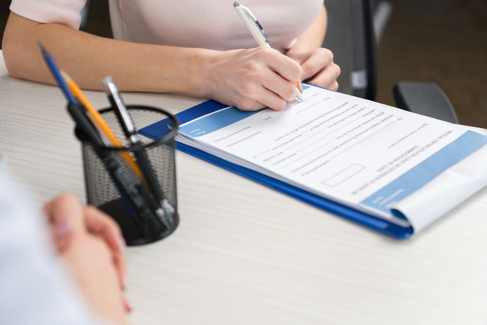 cropped view of patient filling medical form in professional clinic