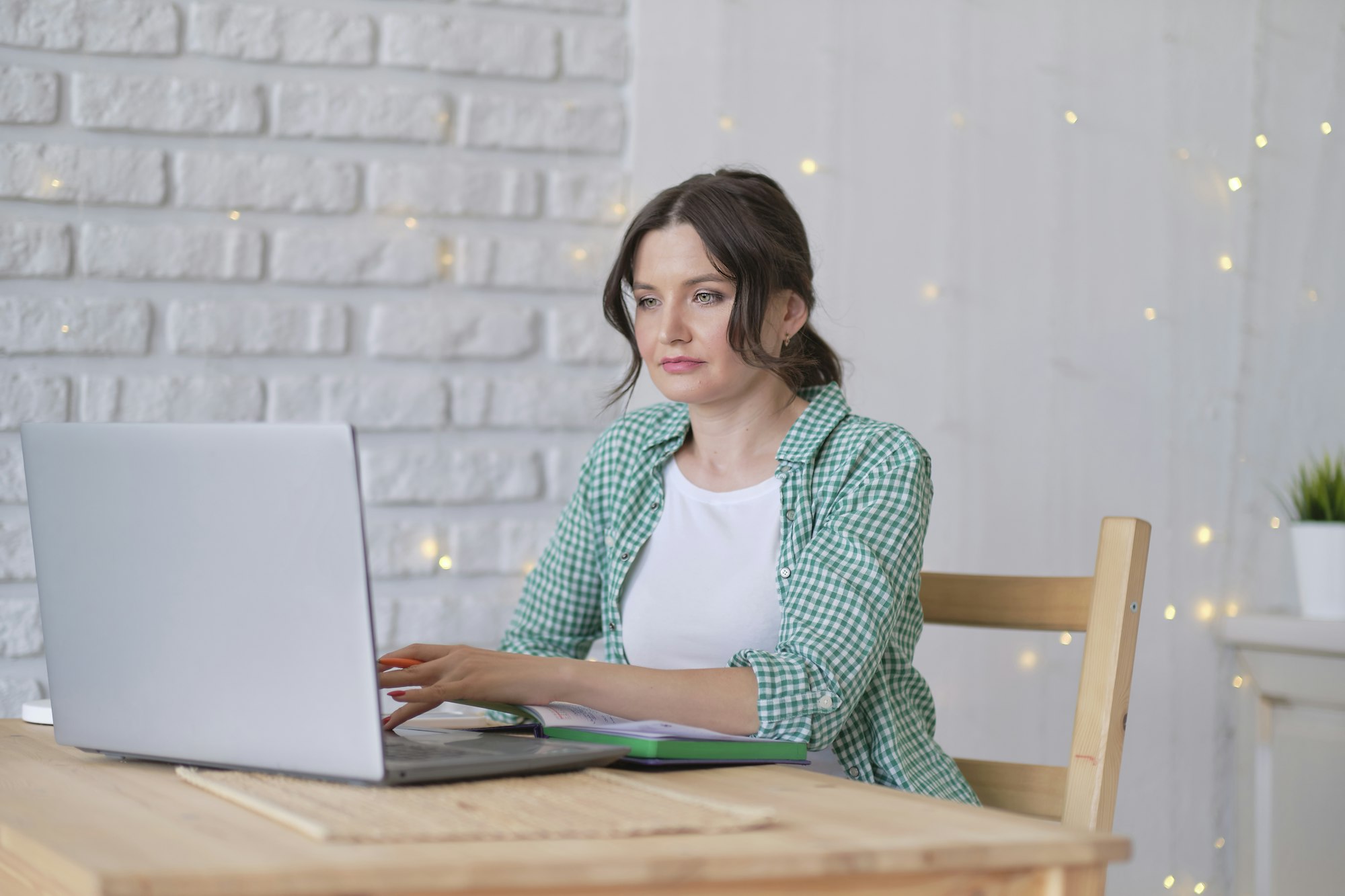 woman sitting at a table working at a laptop computer. concept of remote work from home.