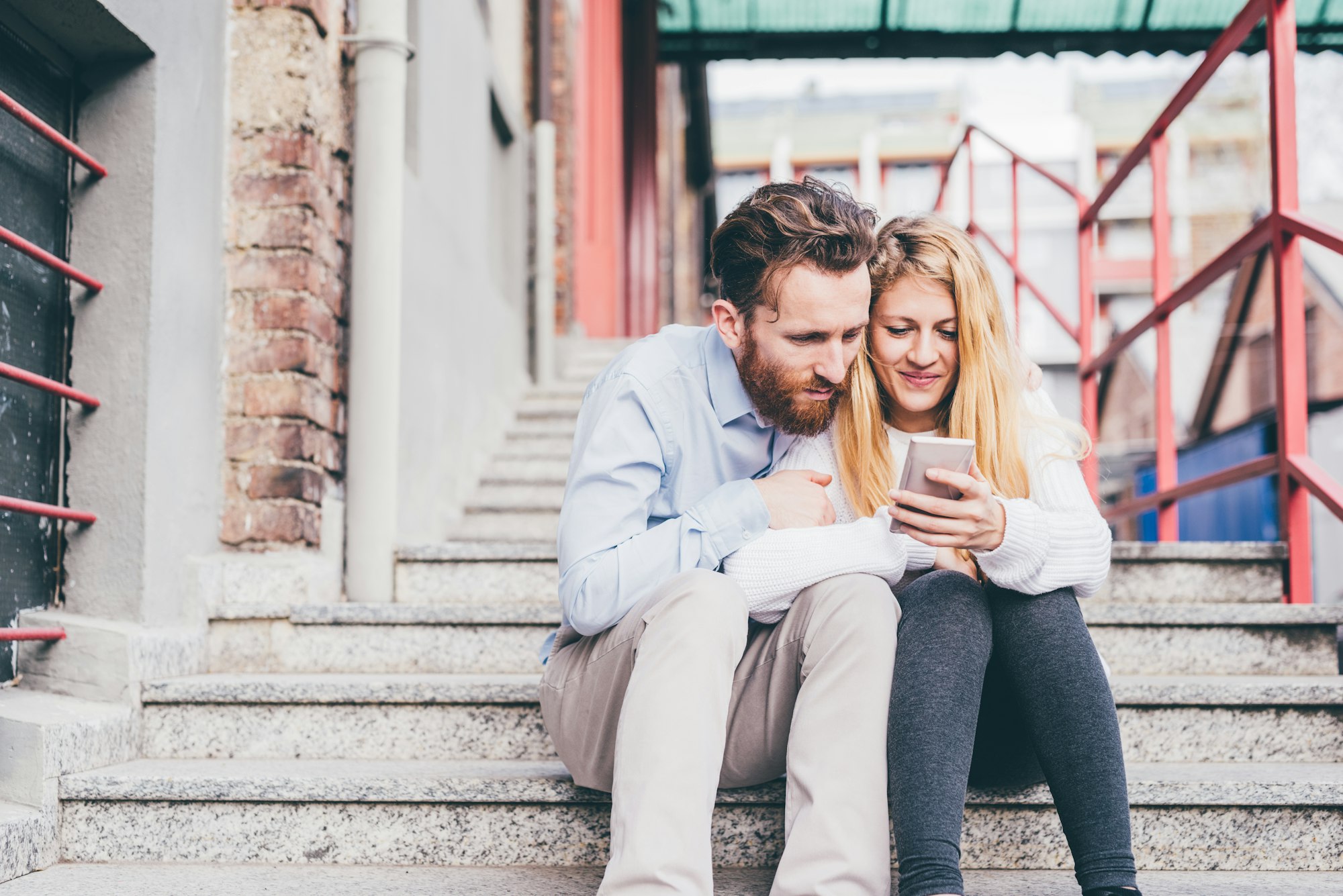 Young couple outdoors using smartphone smiling shopping or booking online together